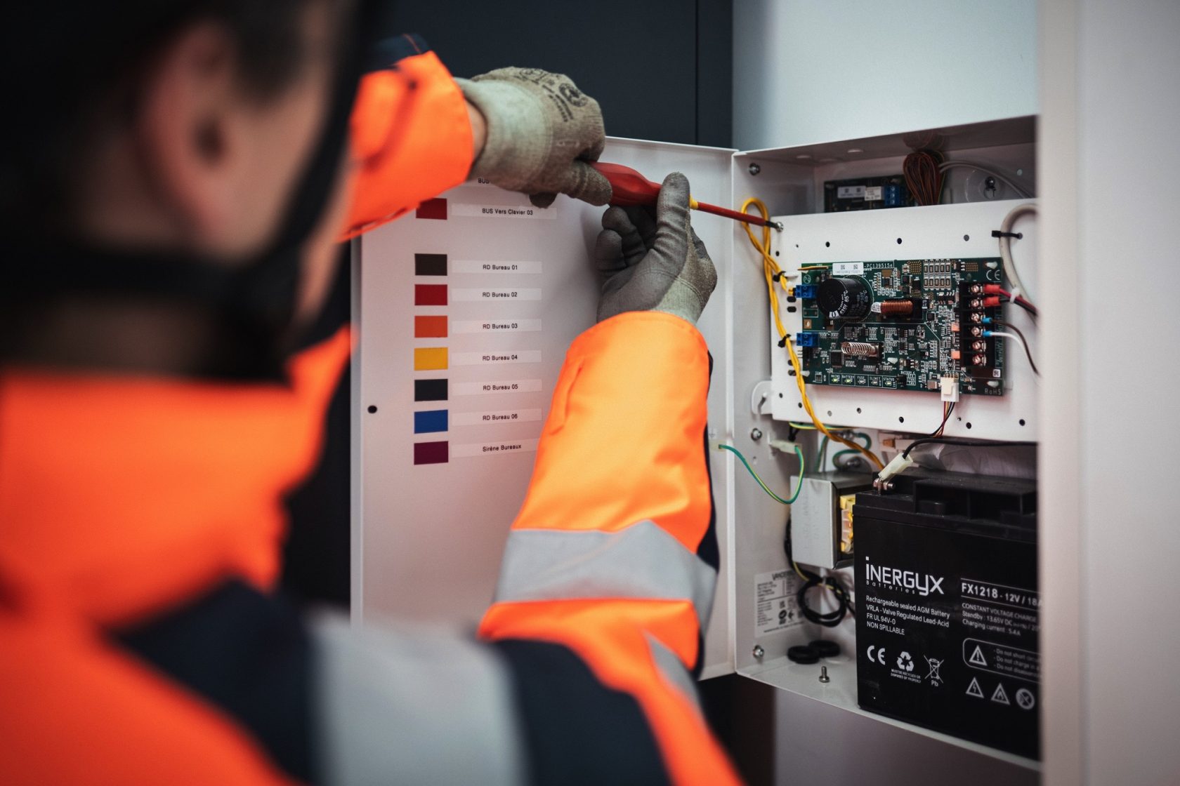 Photo d'un technicien travaillant avec un tournevis dans un tableau d'alarme